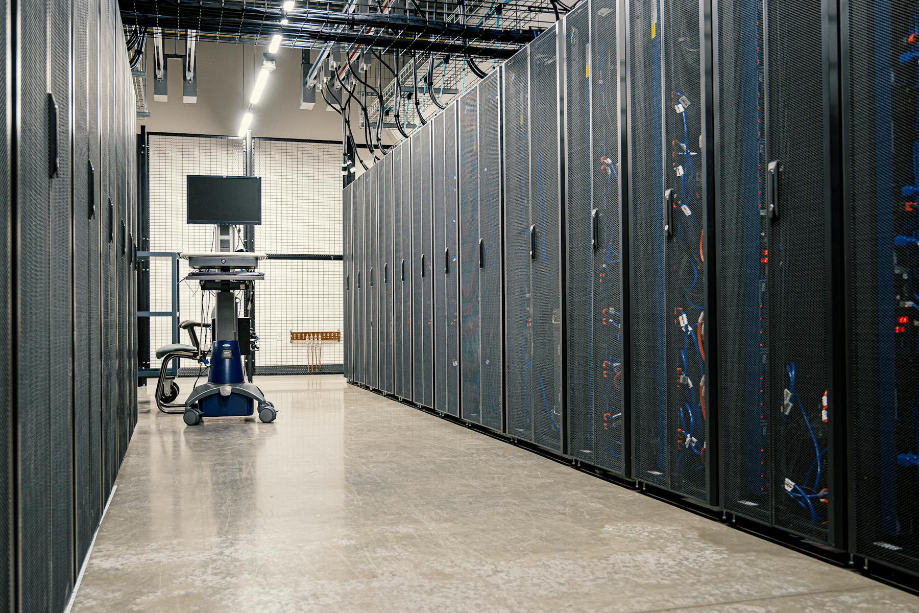 A long aisle of server racks with a mobile KVM cart